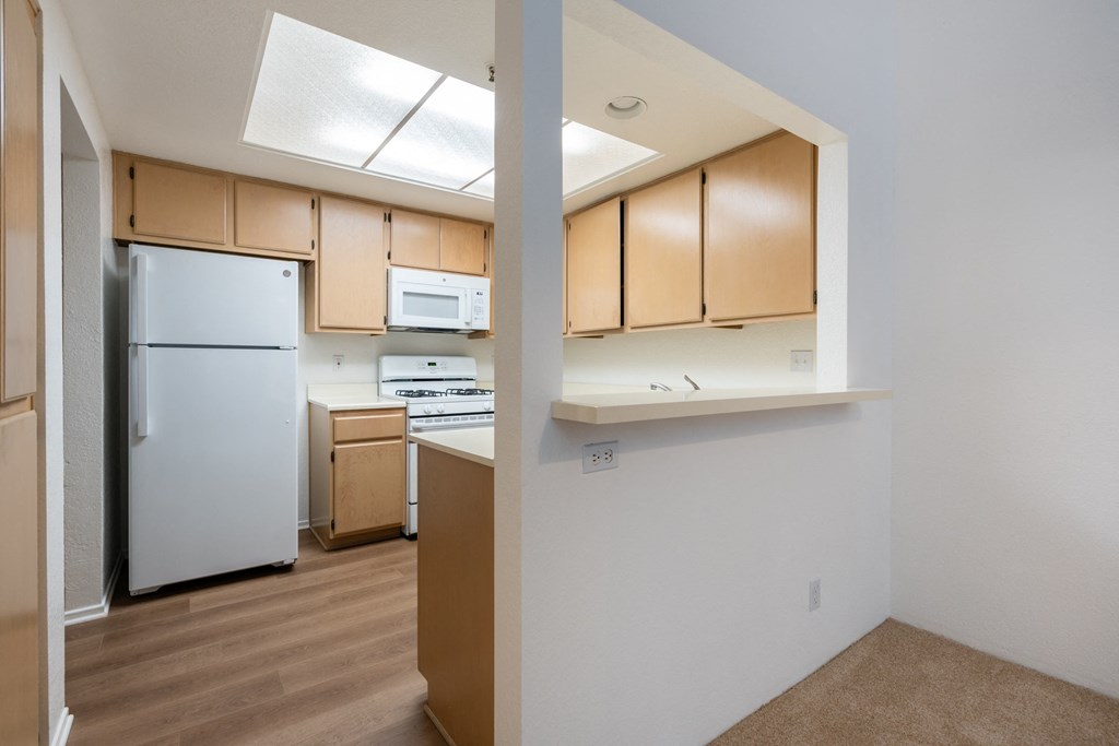 an empty kitchen with white appliances and wooden cabinets