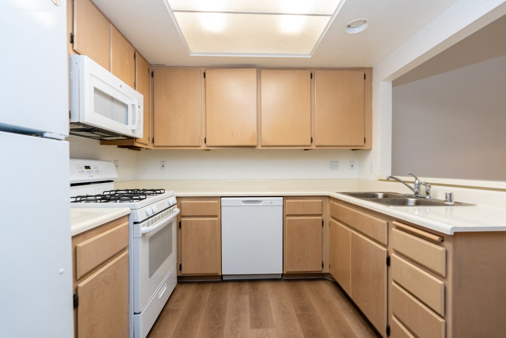 an empty kitchen with white appliances and wooden cabinets