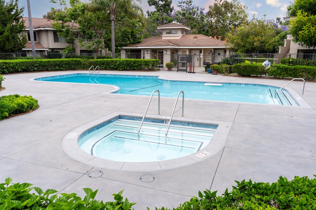 a pool and spa with a house in the background