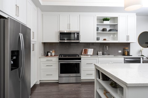 A modern kitchen with white cabinets and stainless steel appliances.