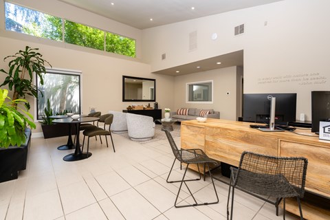 A modern living room with a wooden desk and black chairs.