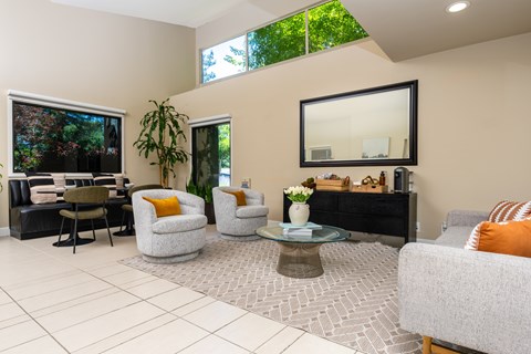 A living room with a grey couch, a coffee table, and a large mirror on the wall.