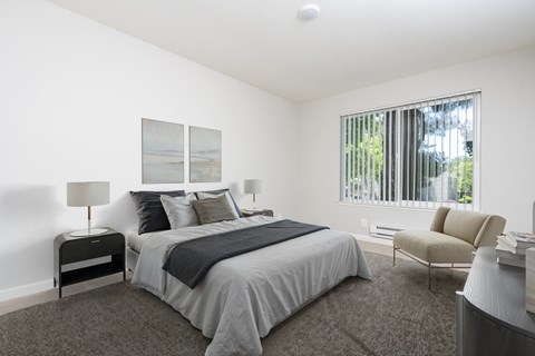 A bedroom with a large bed and a chair.