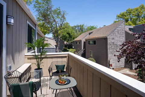 A patio with a table and chairs overlooking a backyard.