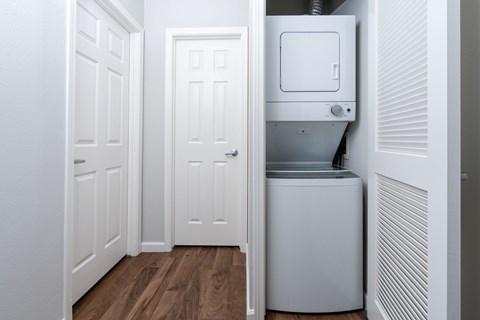 A white door is open to reveal a white tankless water heater.