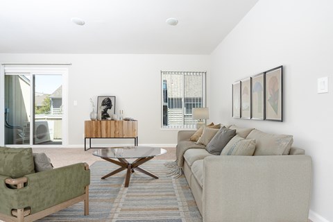 A living room with a green couch, a coffee table, and a large window.