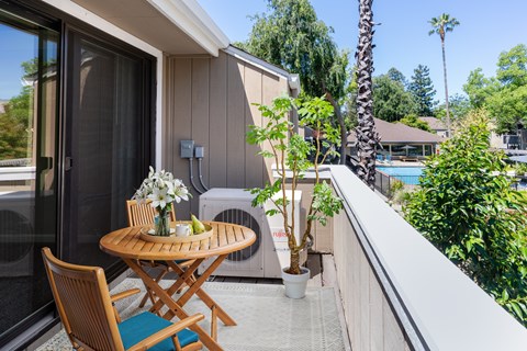 A patio with a table and chairs overlooking a pool.