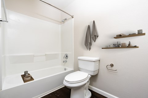 A white toilet sits next to a white bathtub in a bathroom.