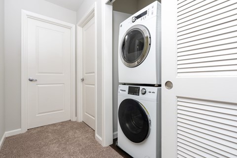 A white washing machine is in a small room with a carpeted floor.