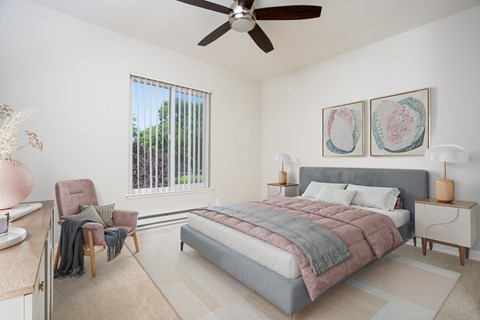 A bedroom with a large bed, a chair, and two framed pictures on the wall.