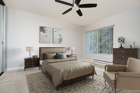 A bedroom with a large bed, a ceiling fan, and a chair.