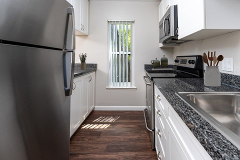 A kitchen with a refrigerator on the left and a sink on the right.
