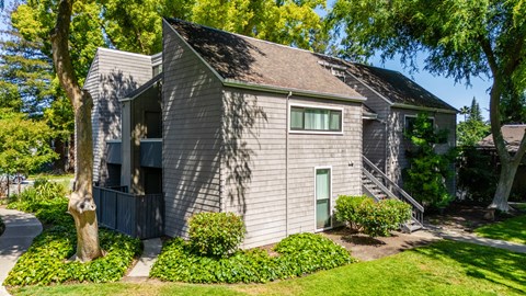 A house with a green lawn and trees in the background.