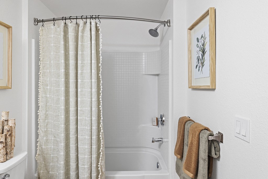 The Edge Milpitas CA a bathroom with white walls and a white bathtub with a shower curtain