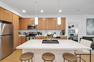 The Edge Milpitas CA a kitchen with wooden cabinets and a white island with four stools