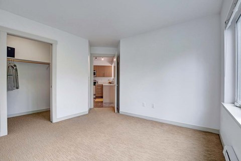 A spacious room with a closet and a doorway leading to another room.