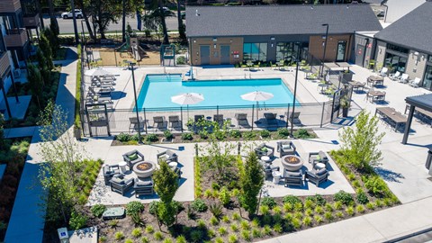 A pool surrounded by a small garden and a few chairs.