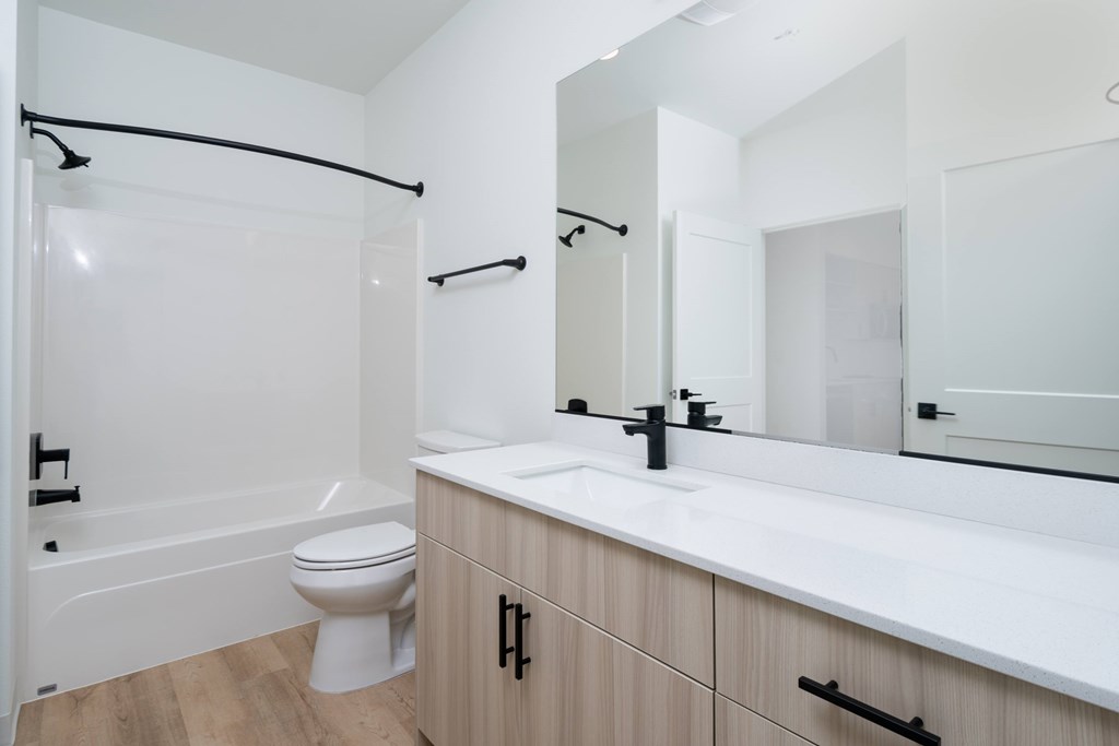 A white bathroom with a toilet, sink, and mirror.