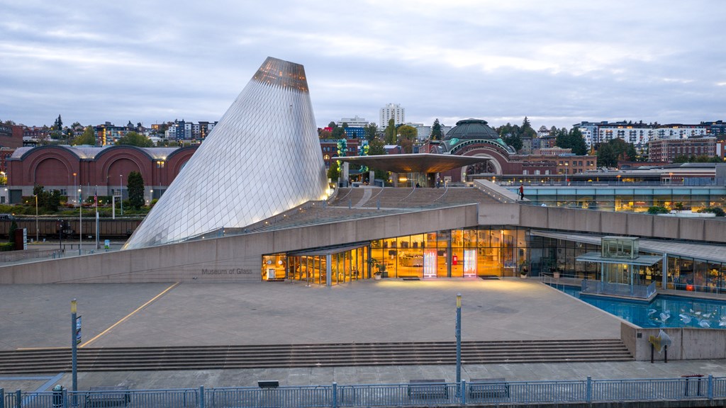 A modern building with a unique triangular roof is illuminated at dusk.