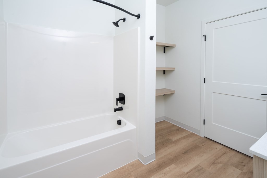 A white bathroom with a bathtub and a white door.