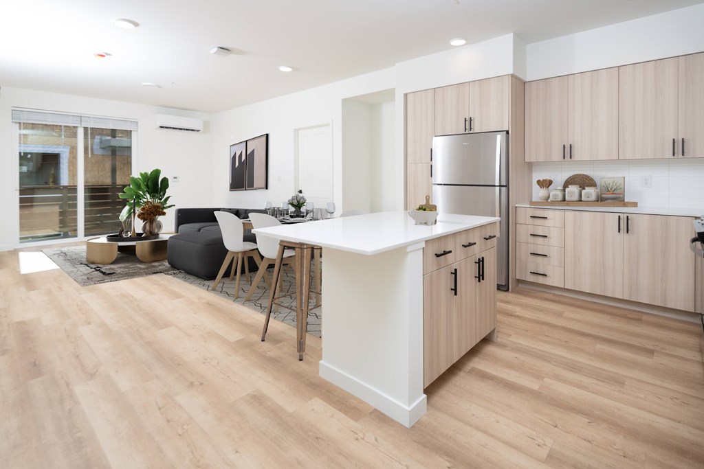 A modern kitchen with wooden floors and a white island.