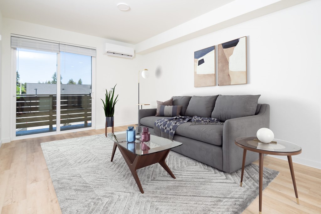 A living room with a grey couch, a coffee table, and a plant.