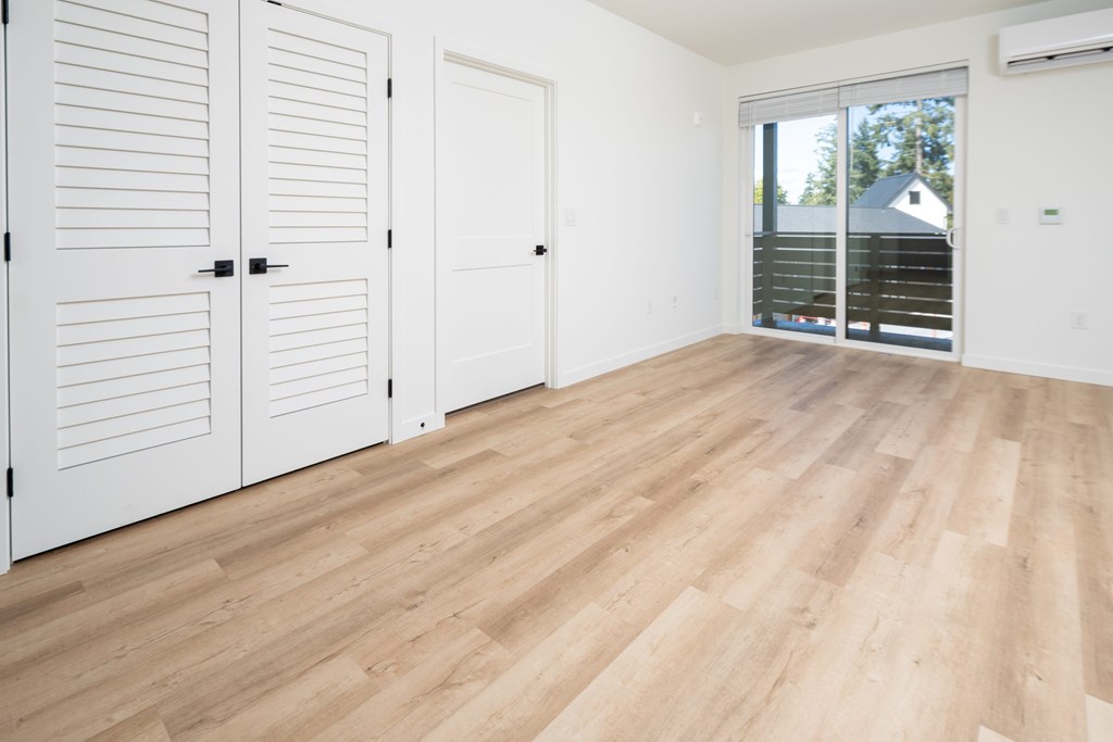 Closed white doors with black handles on a white wall.