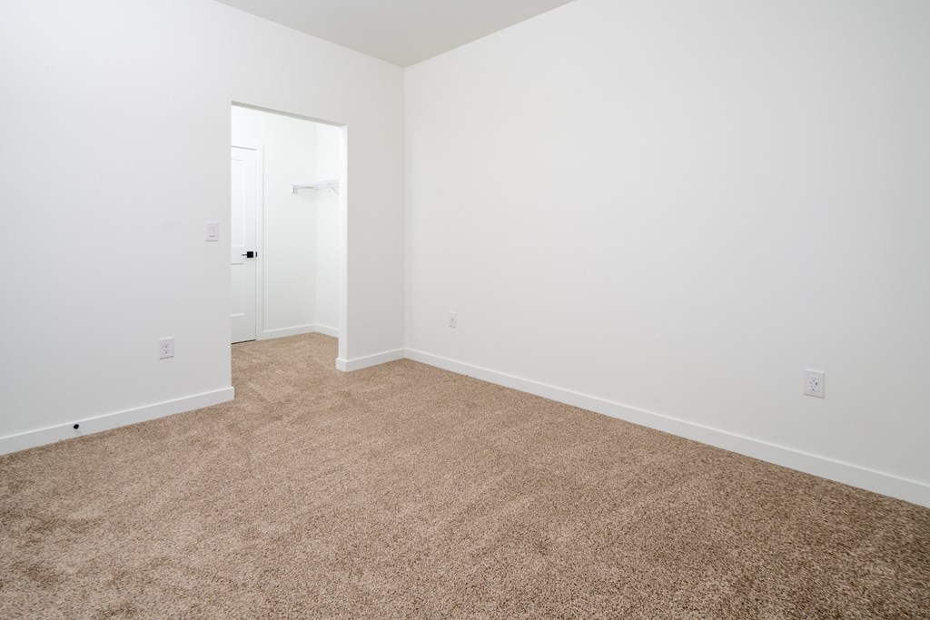 A room with a carpeted floor and a doorway leading to another room.