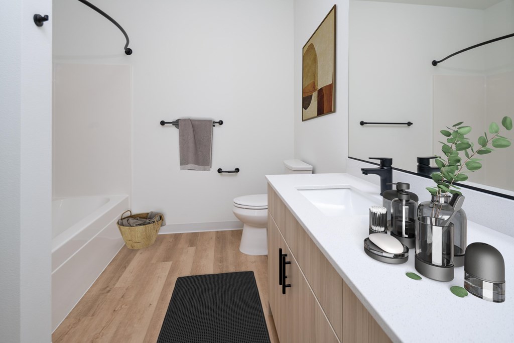 A bathroom with a white toilet, a white sink, and a black mat on the floor.