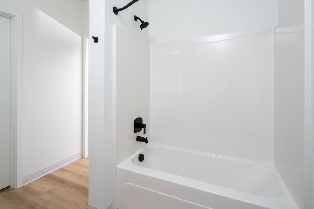 A white bathroom with a tub and a towel rack.