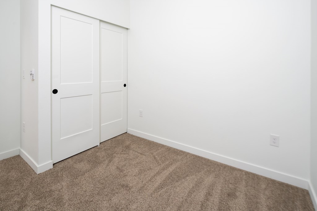 A room with a carpeted floor and two white doors.