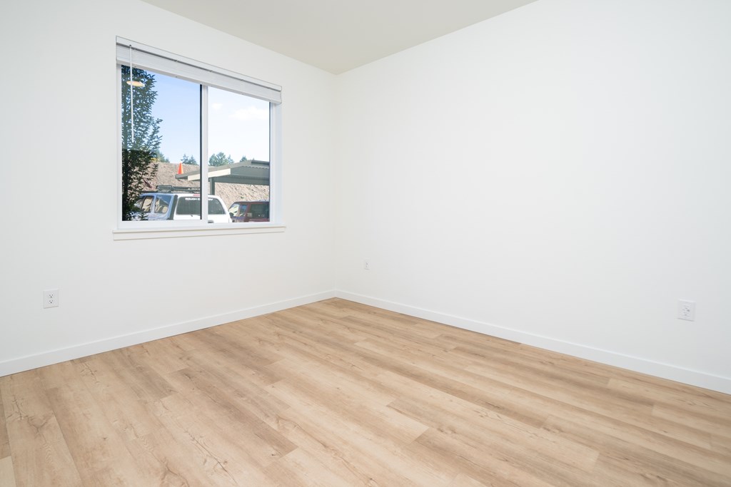 A room with a window and wooden flooring.