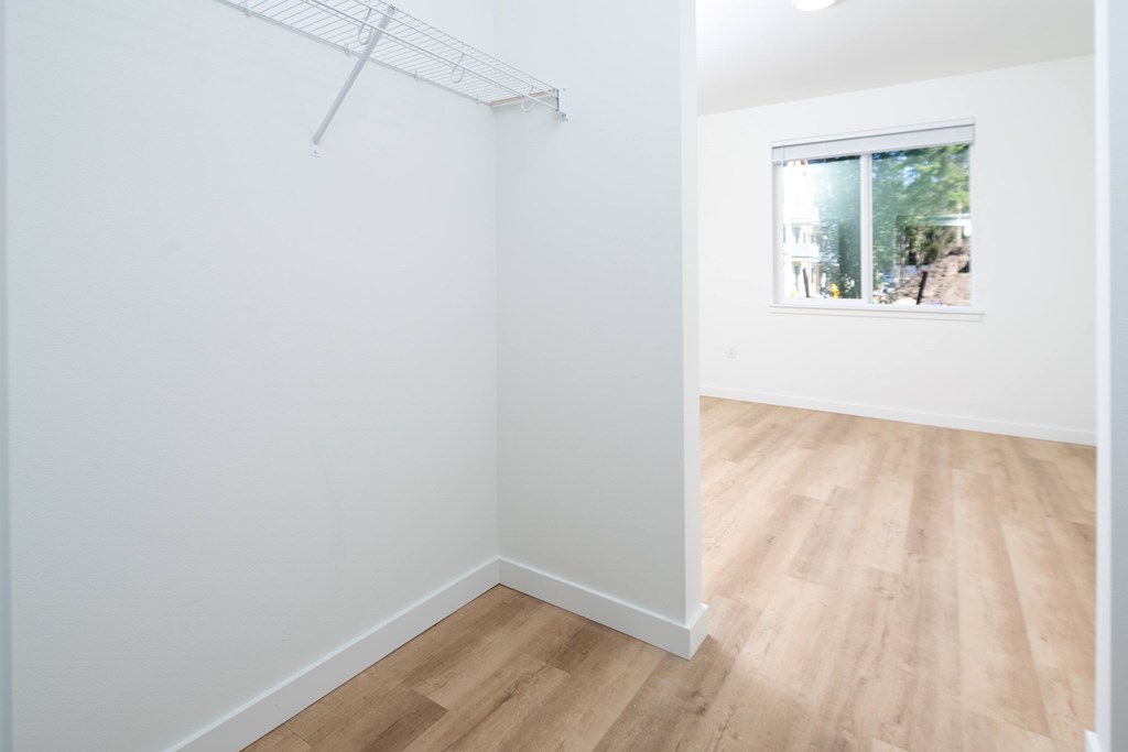 A white wall with a clothes rack and a window.
