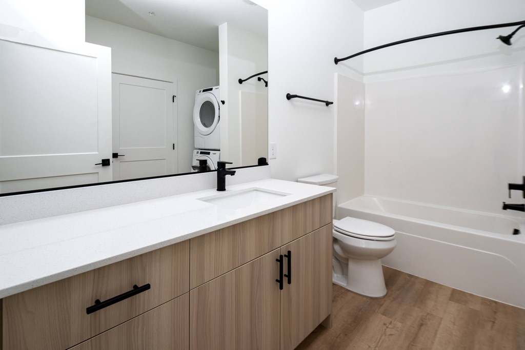 A white bathroom with wooden cabinets and a white toilet.