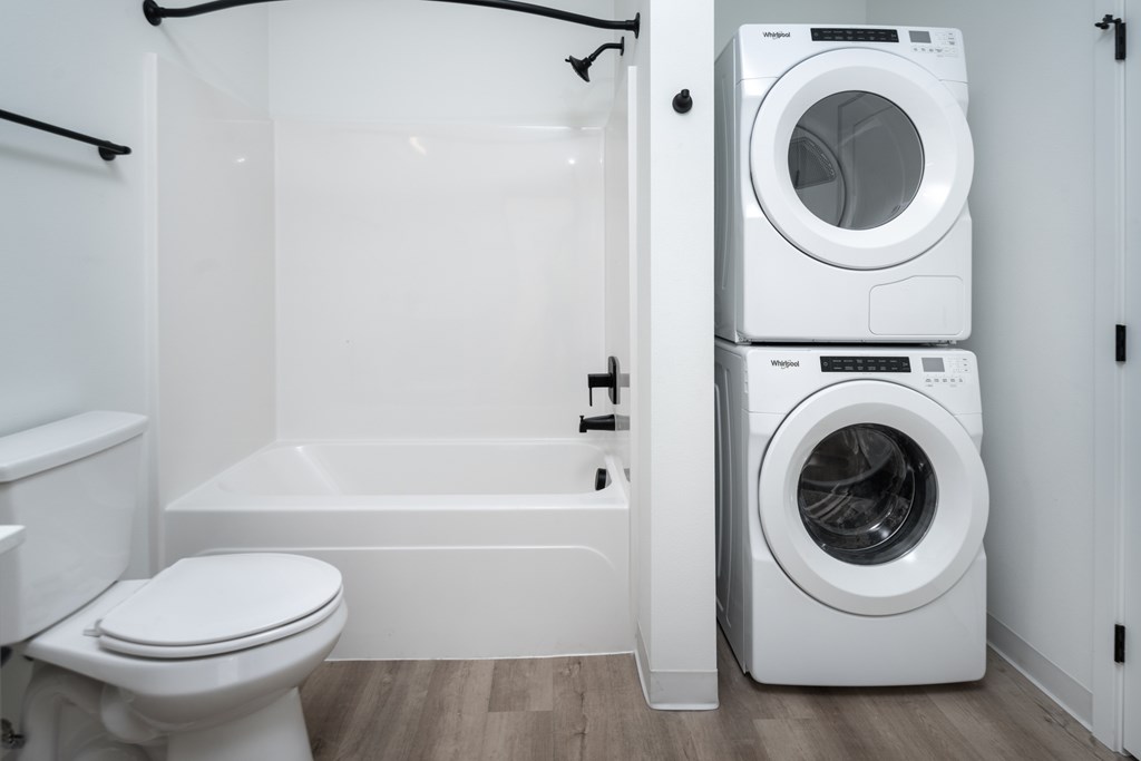 A white bathroom with a toilet, a bathtub, and a washing machine.