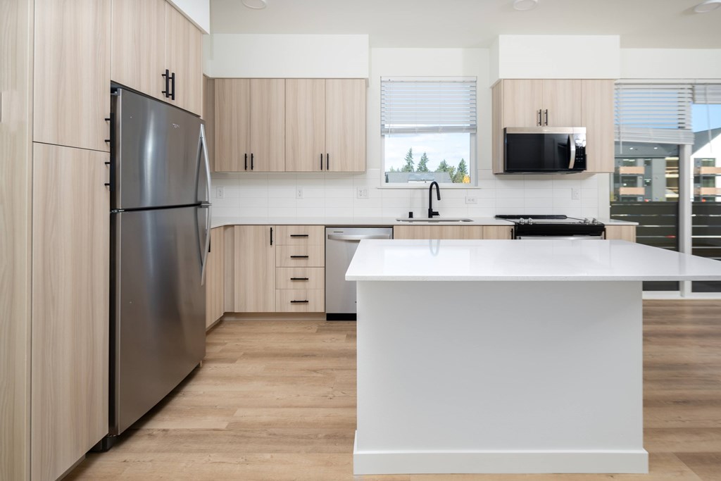 A modern kitchen with a refrigerator, sink, and cabinets.