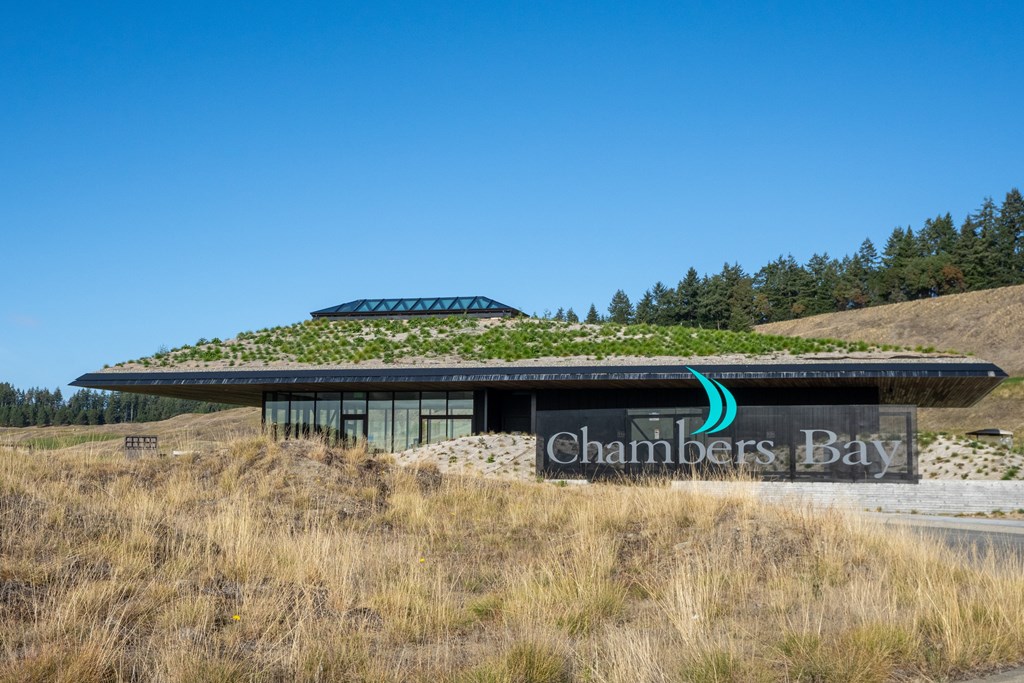 A modern building with a green roof and a sign that reads "Chambers Bay.".