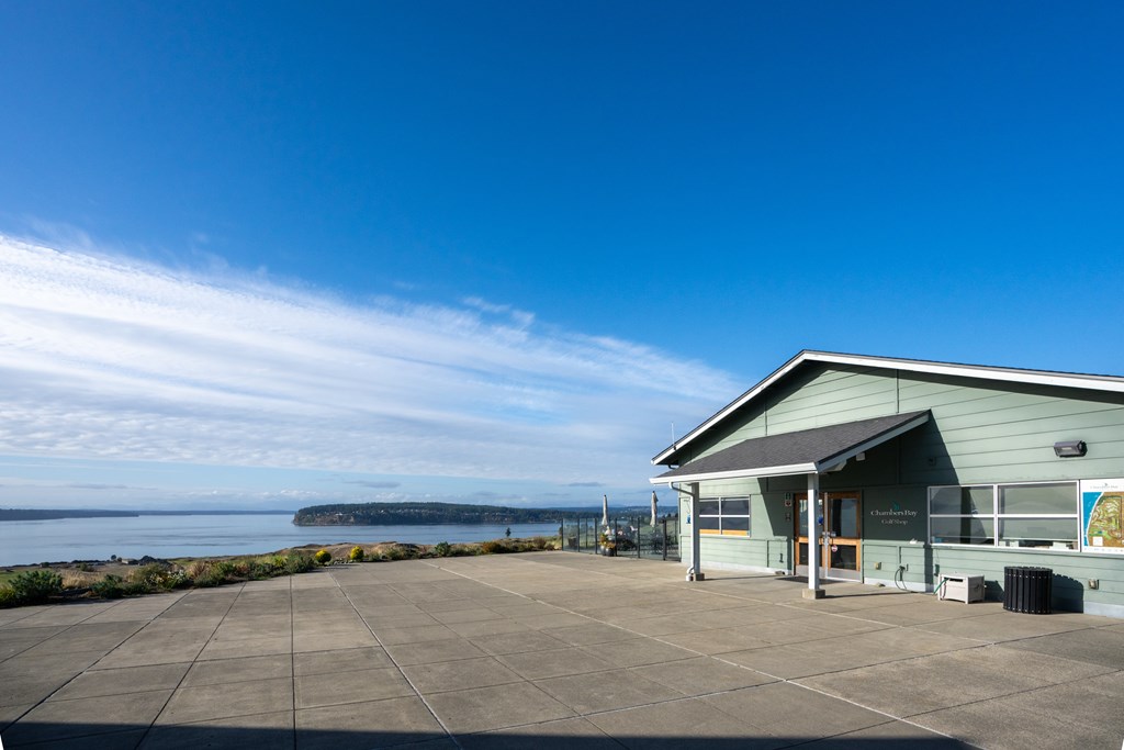 A building with a green roof is situated in front of a body of water.