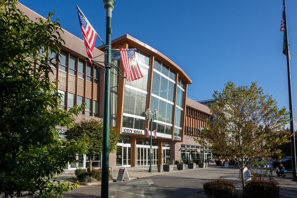 A building with a glass facade and a sign that reads "PETER HALL" is shown with two American flags on flagpoles in front.