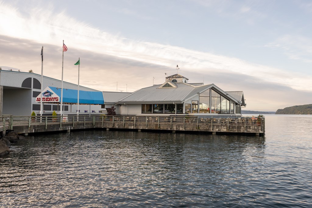 A building with a blue roof is situated on a pier over water.