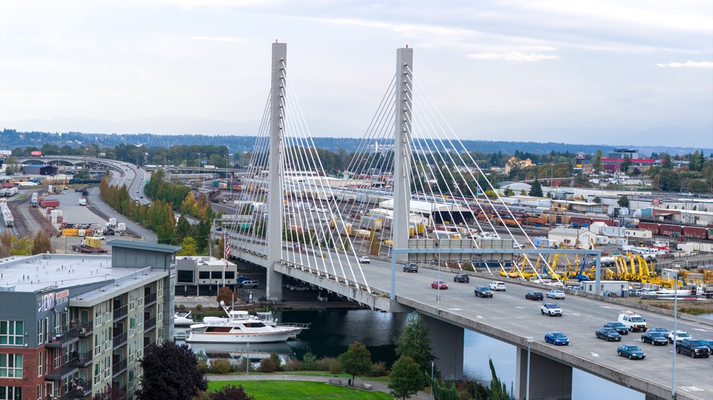 A large white bridge with two towers spans a river with cars driving on it.