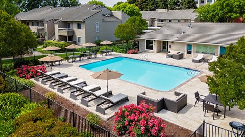 A pool surrounded by lounge chairs and umbrellas.