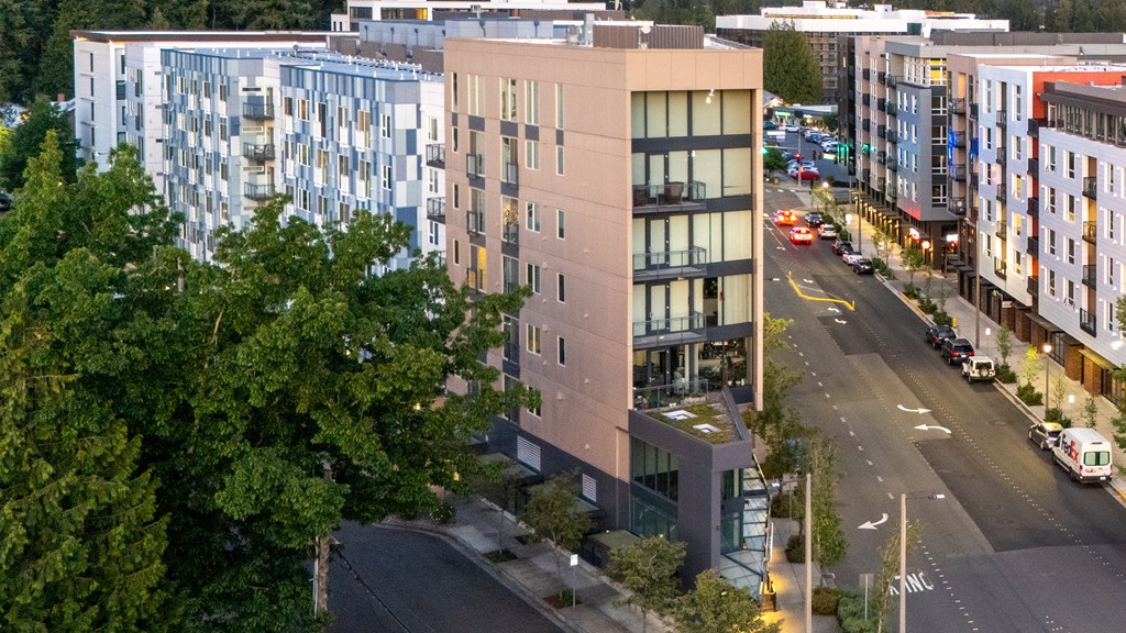 A modern building with a glass facade is situated on a street corner with a traffic light.