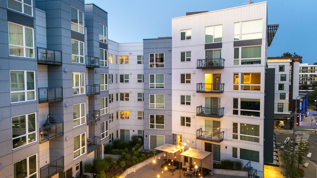 A modern apartment complex with balconies and lights on.