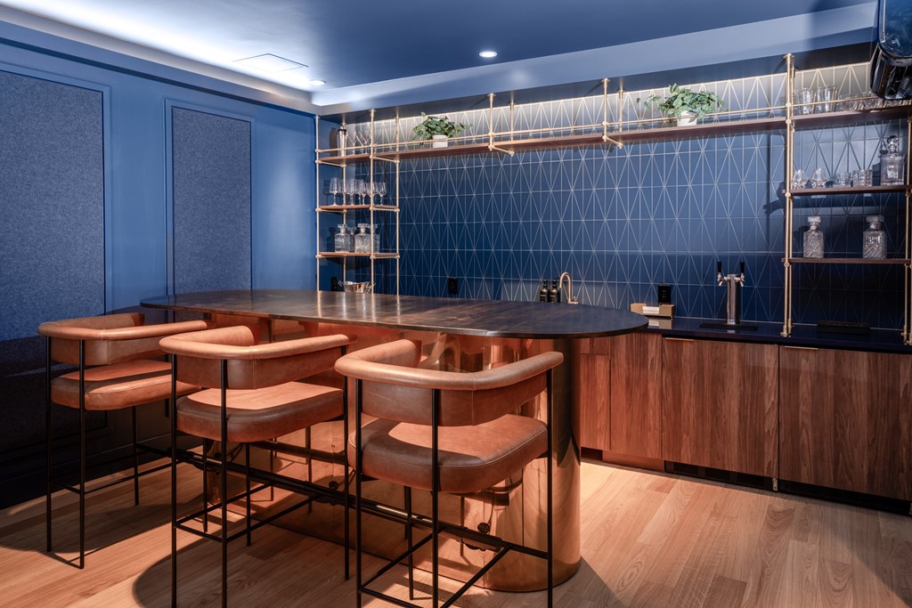 A bar with a black counter and brown stools.