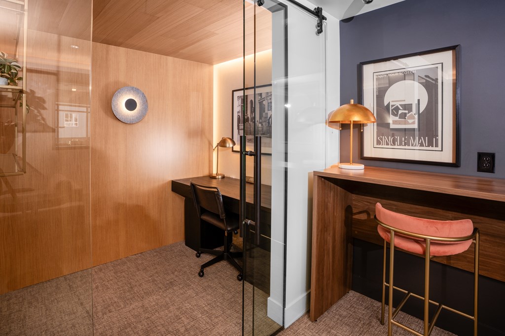 A room with a desk, chair, and a framed picture on the wall.