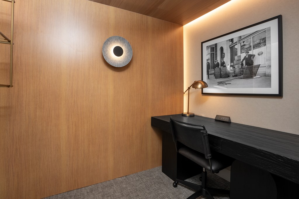 A modern office with a wooden desk and a black chair.