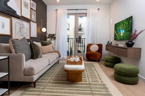 A living room with a couch, chair, ottoman, and a painting on the wall.