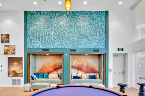 A room with a pool table and a wall with a painting of a woman's face.