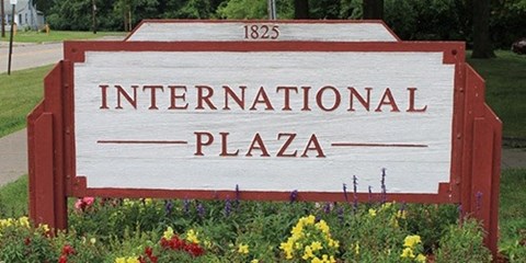 a sign for international plaza in front of a garden